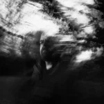 Ethereal figure amidst dark, swirling trees.