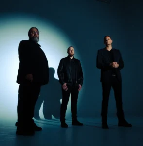 Three figures in dramatic lighting. Pure Obsessions & Red Nights